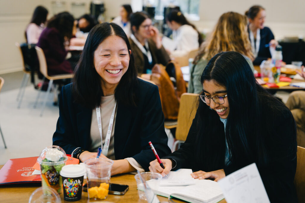 Two high school students smile as they work.