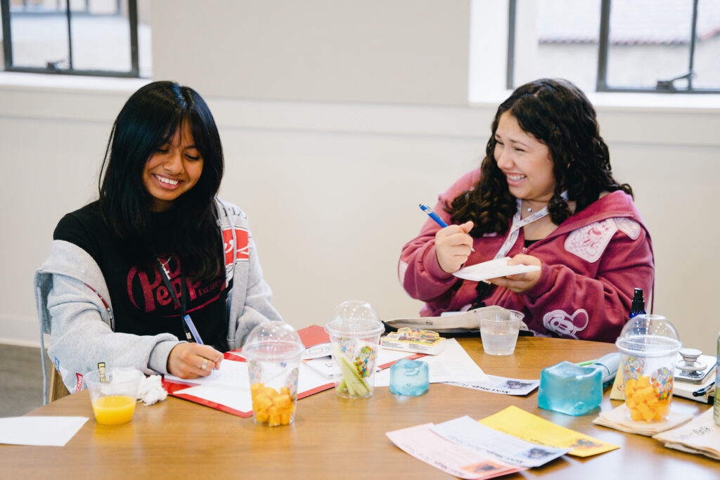 Two high schoolers laugh together.