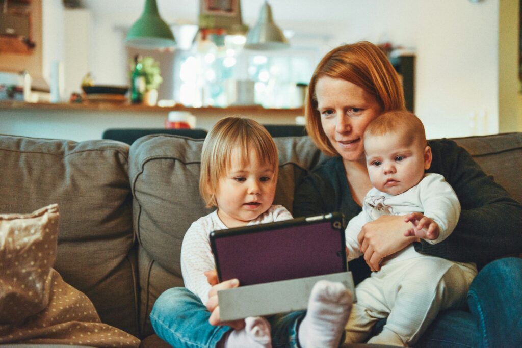 A mother and two children consult a tablet together.