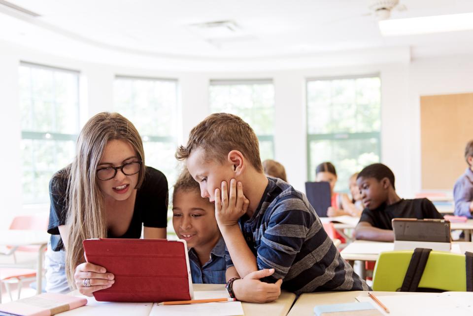 A student and instructor look at a digital tablet.