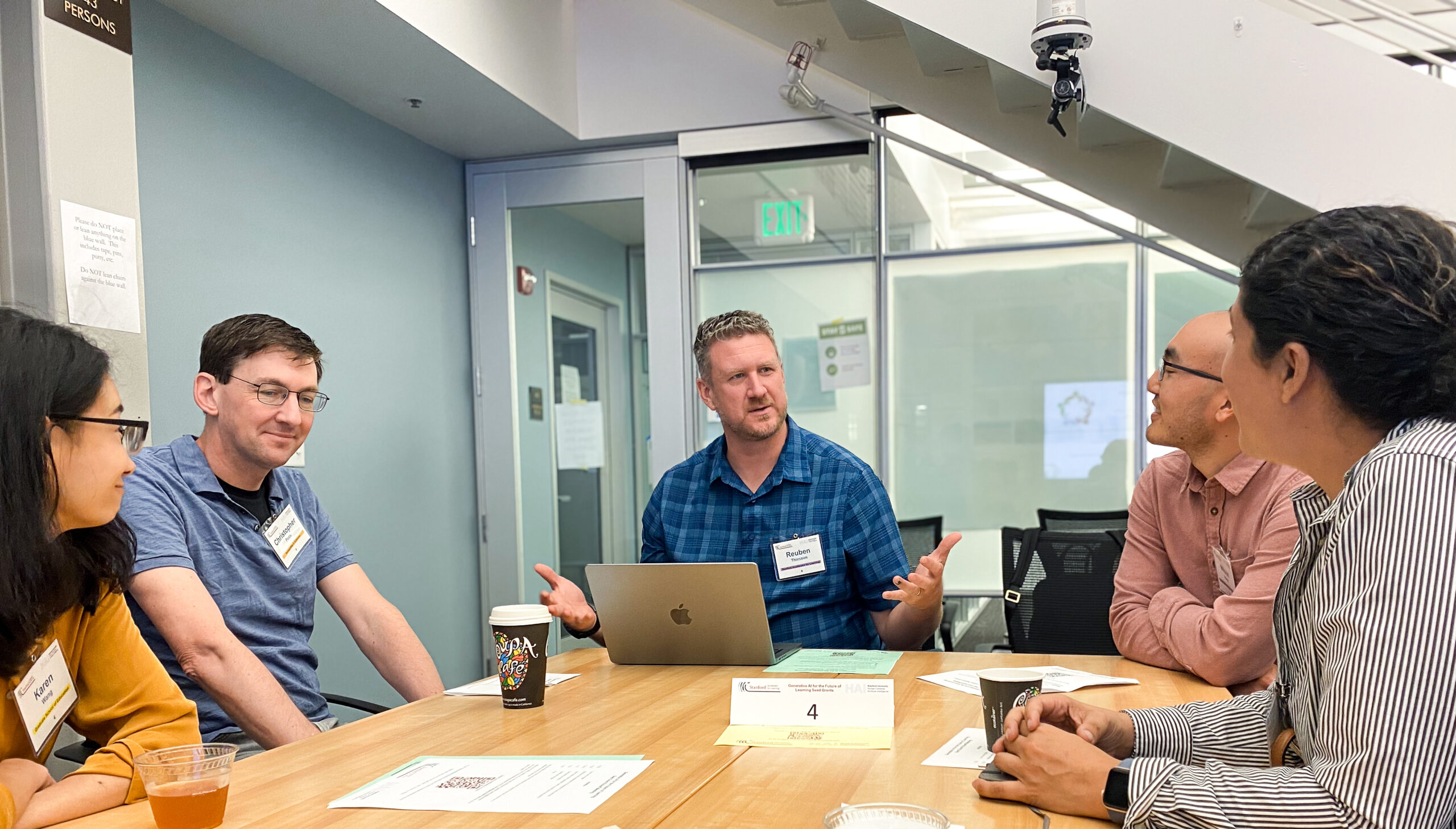 Reuben Thiessen chats with a group of people around a conference table.