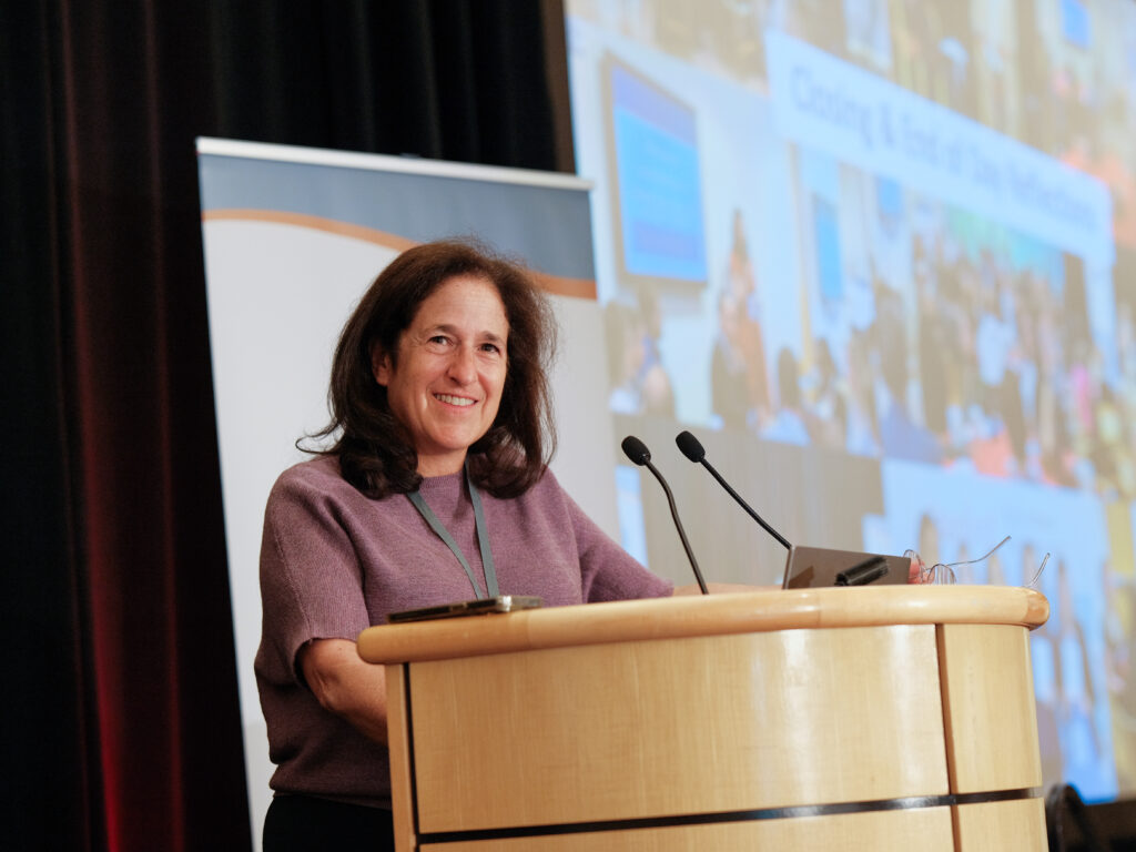 Professor Susanna Loeb stands at a podium in front of a screen.