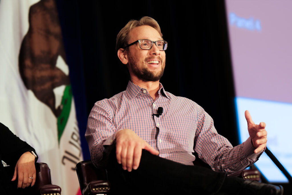 Professor Jason Yeatman speaks on a panel in front of a California flag.