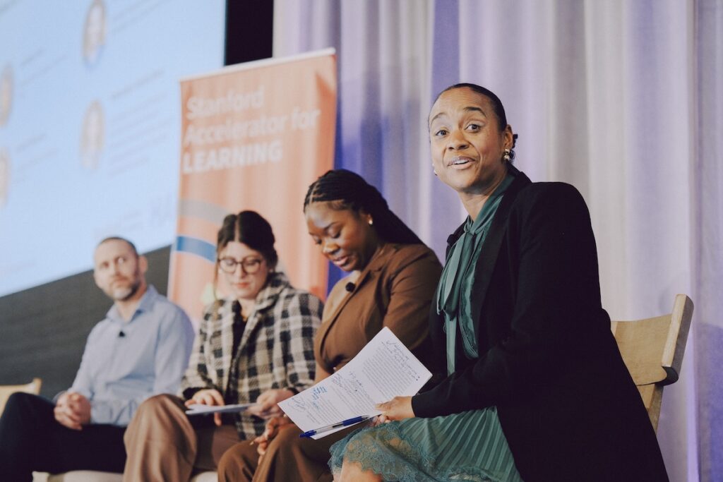 Maisha Winn and three panelists sit onstage.