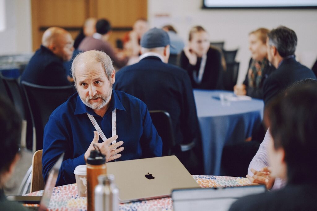A researcher emphatically shares his thoughts at a table with other attendees.