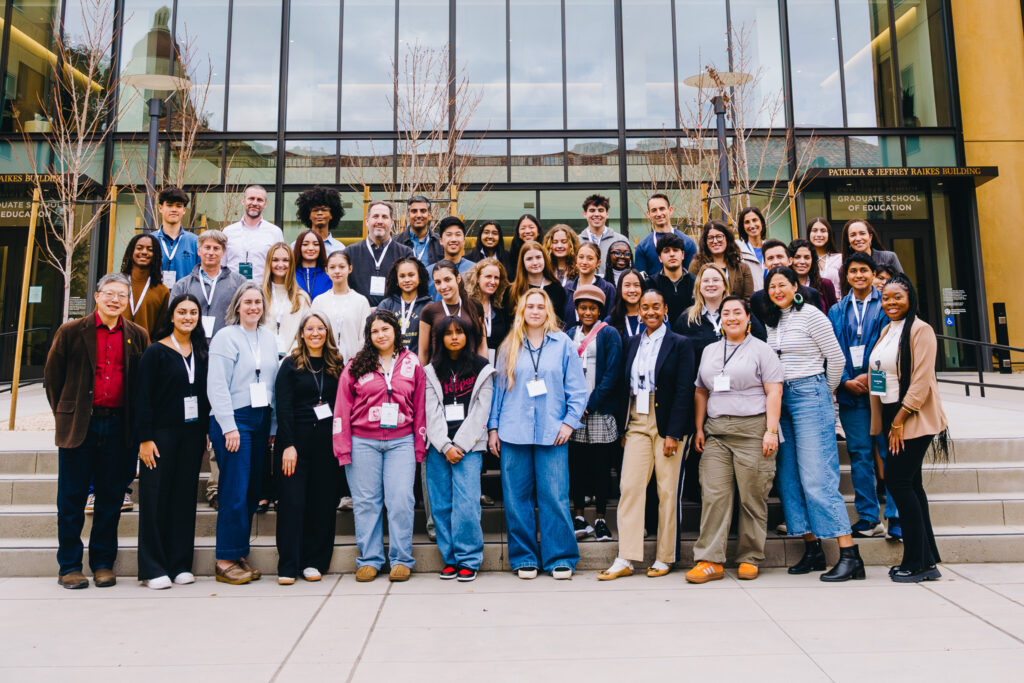 A large group of high school students and teachers pose outside the Stanford Graduate School of Education.