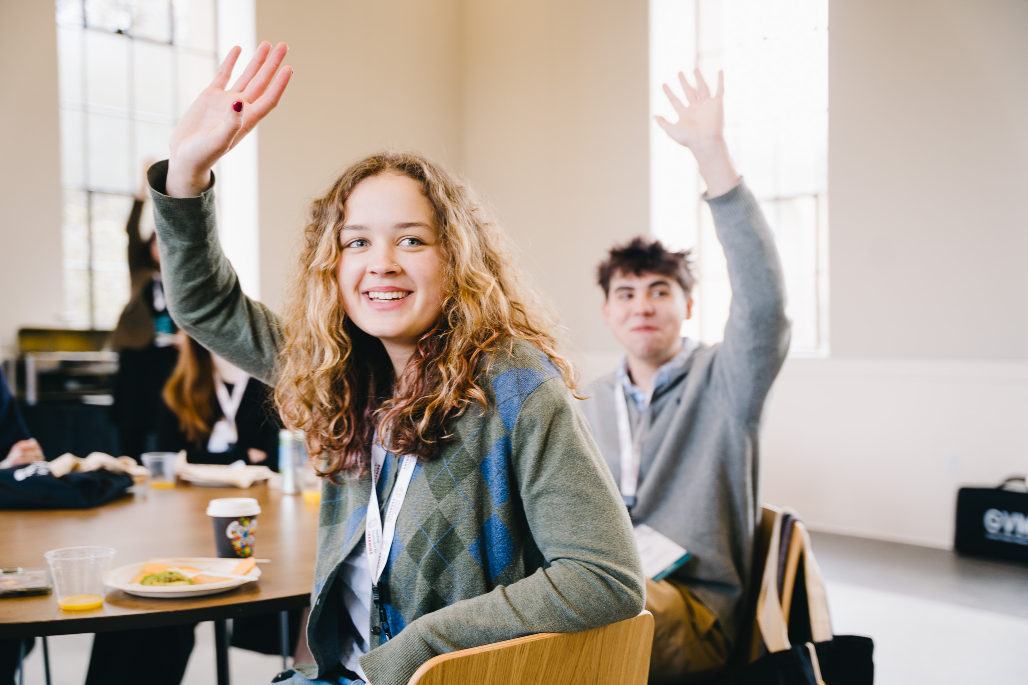 Two high school students raise their hands.