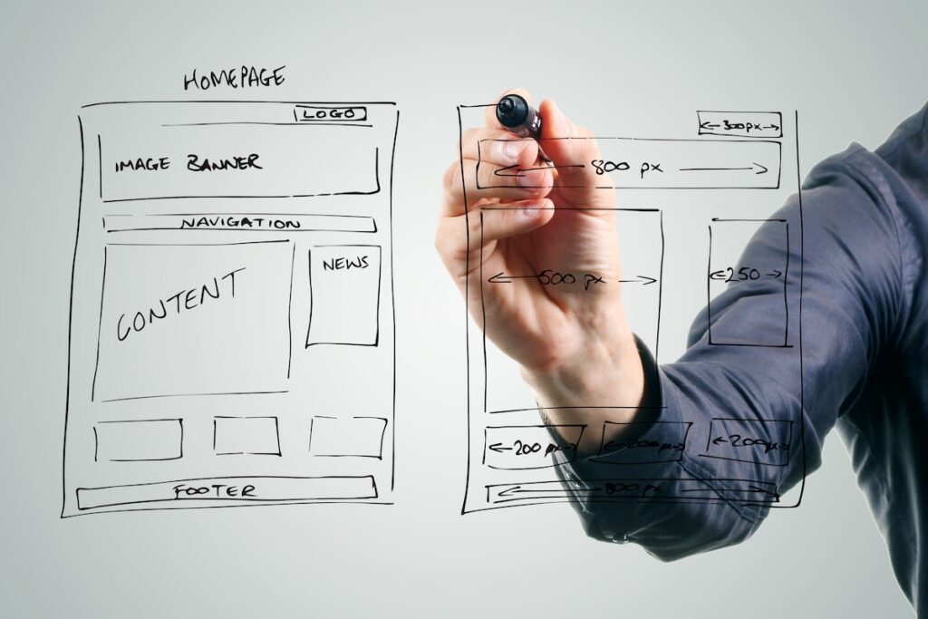 A transparent whiteboard contains hand drawn plans for a website.