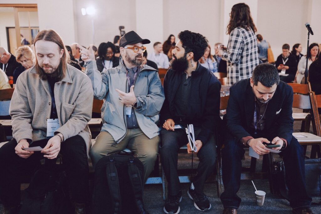 A group of people sit in a room together, chatting before a screening.