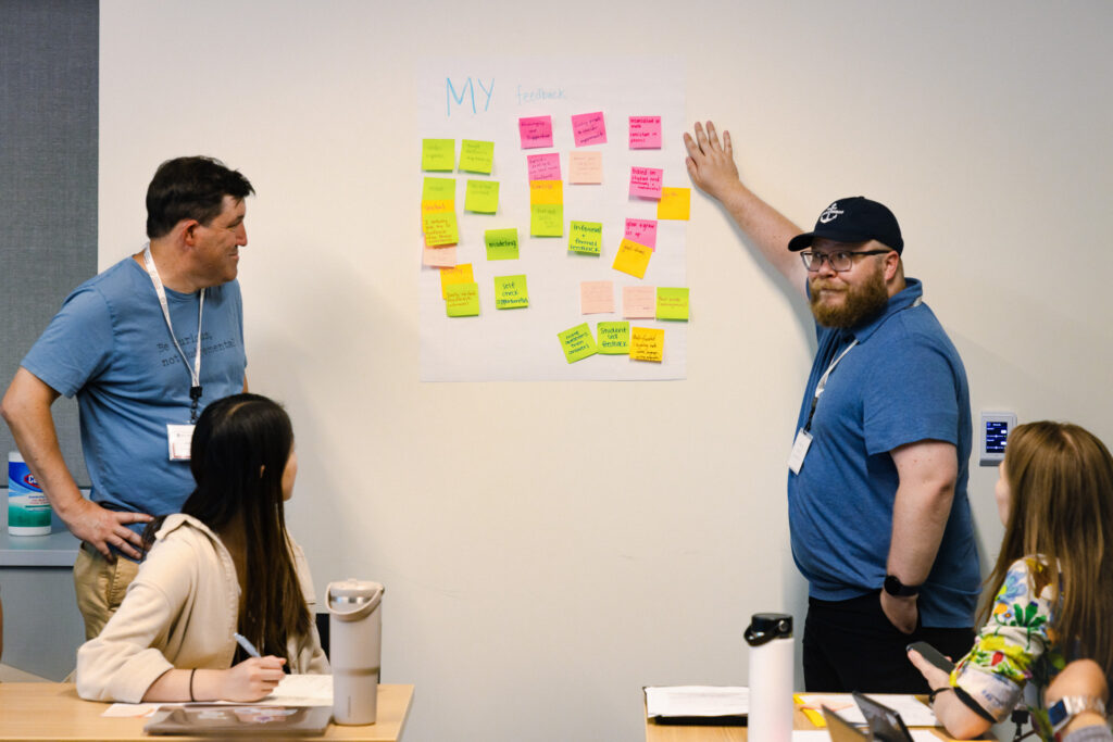 Two educators brainstorm with colleagues using sticky notes.