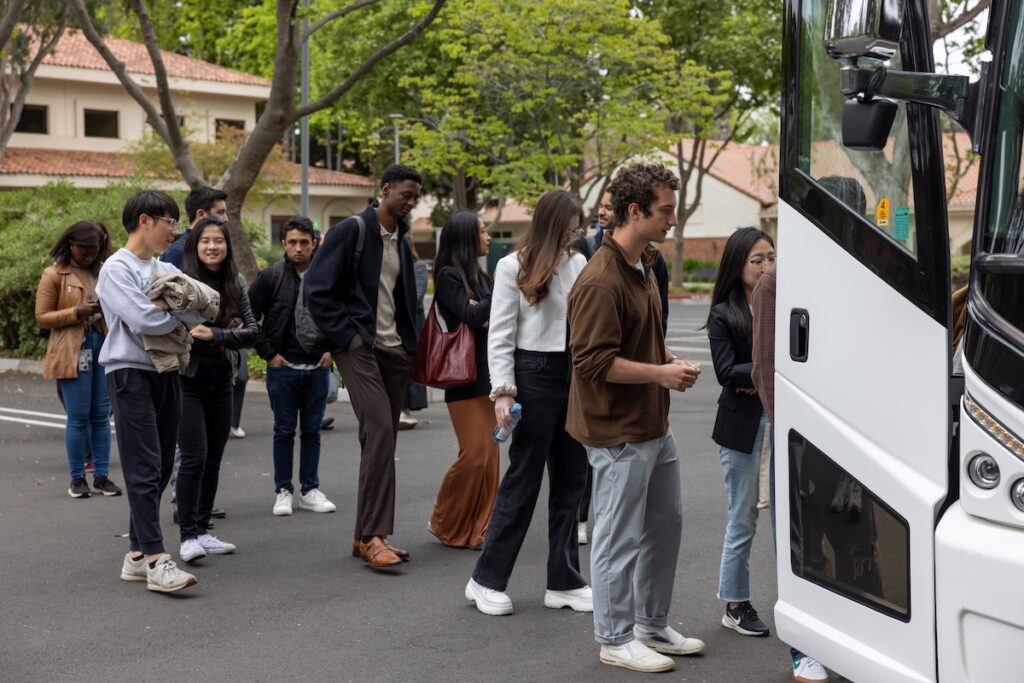 A line of Stanford students board a bus.