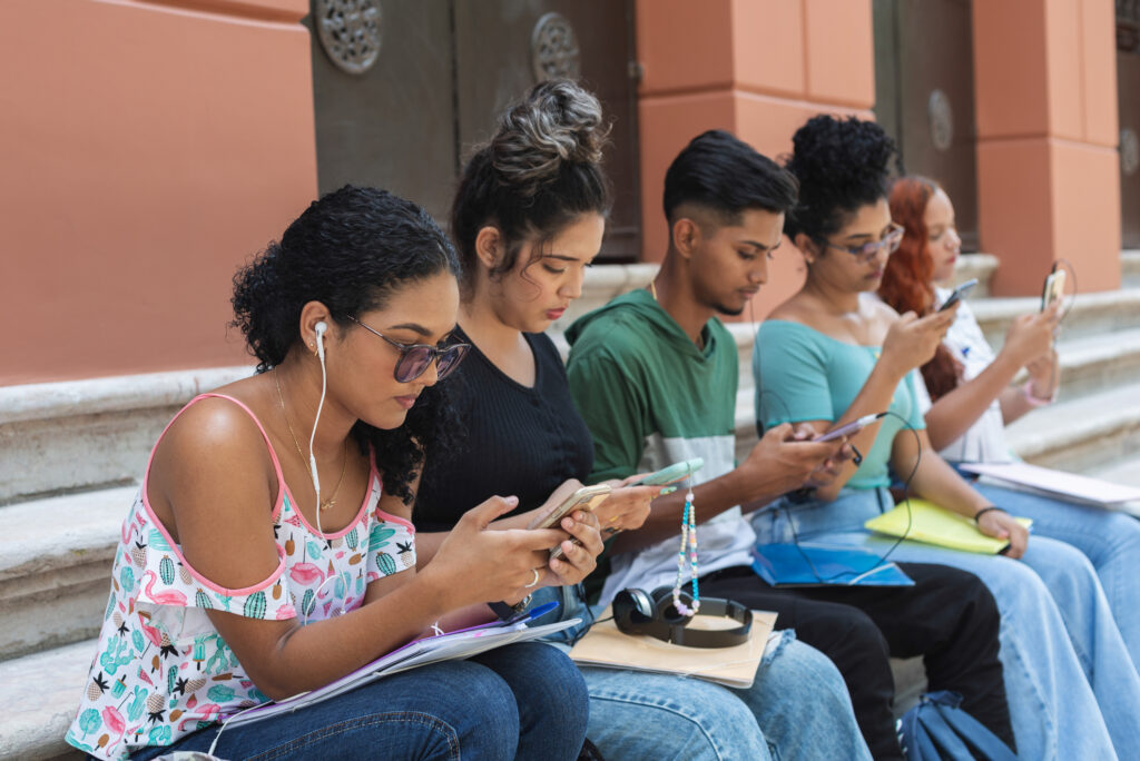 Small group of high school students using their smartphones outdoors.