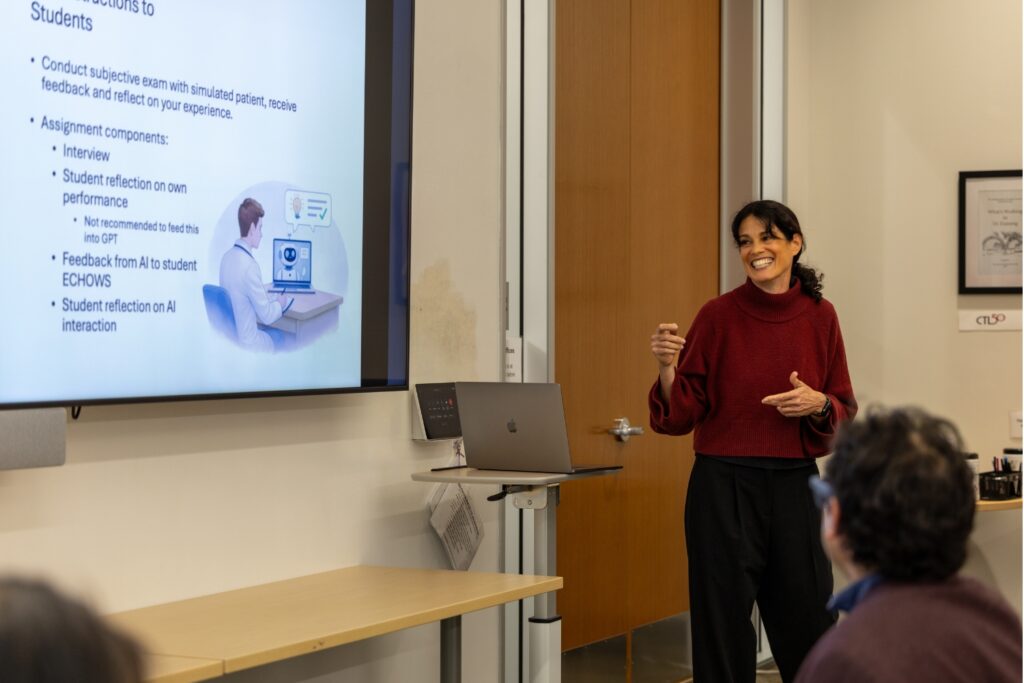 A woman smiles as she presents in a Stanford classroom.