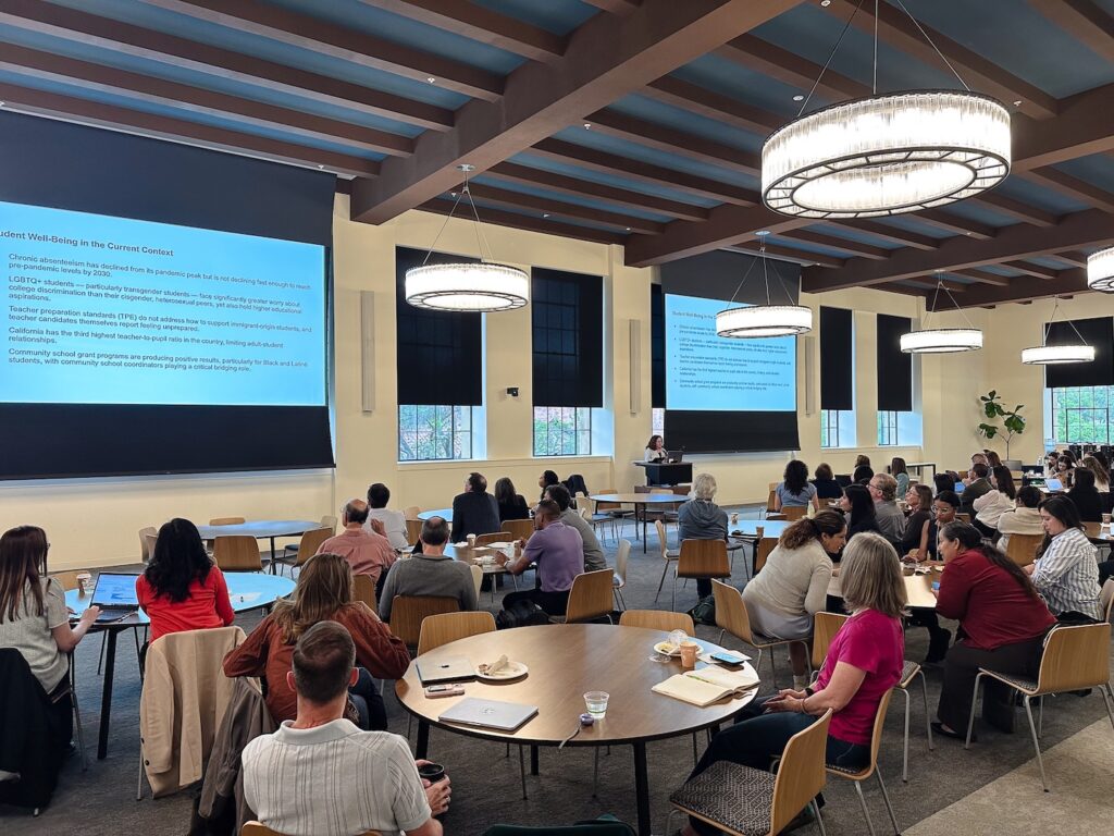 A roomful of researchers gather and sit at round tables.