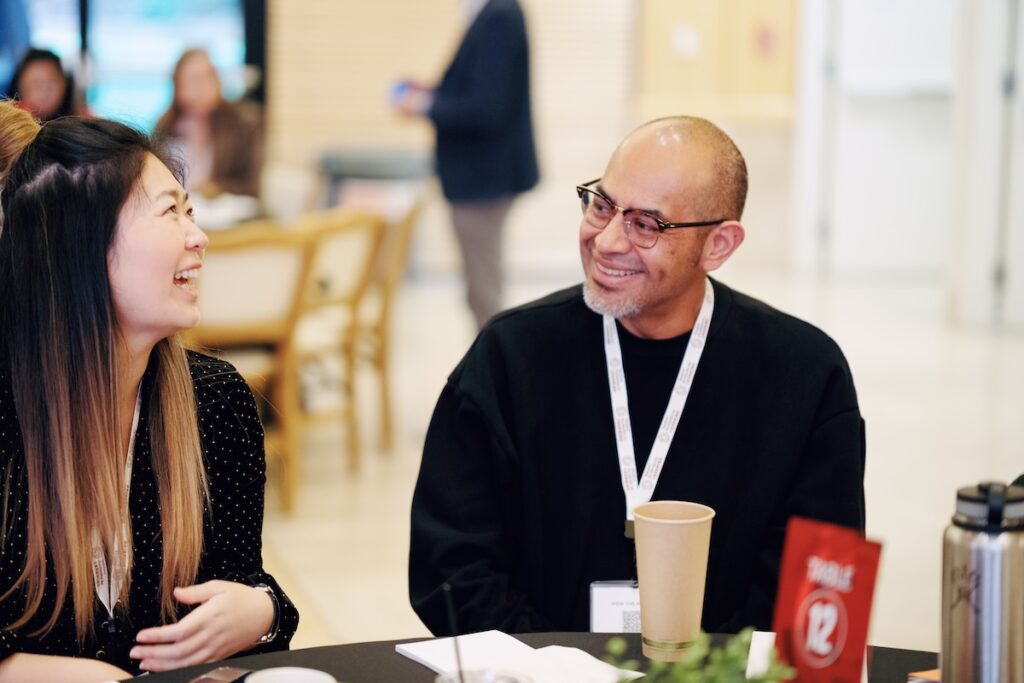 Two attendees smile and laugh at a round table.